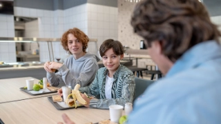 Zwei Kinder essen in der Schulmensa ihr Mittagessen.